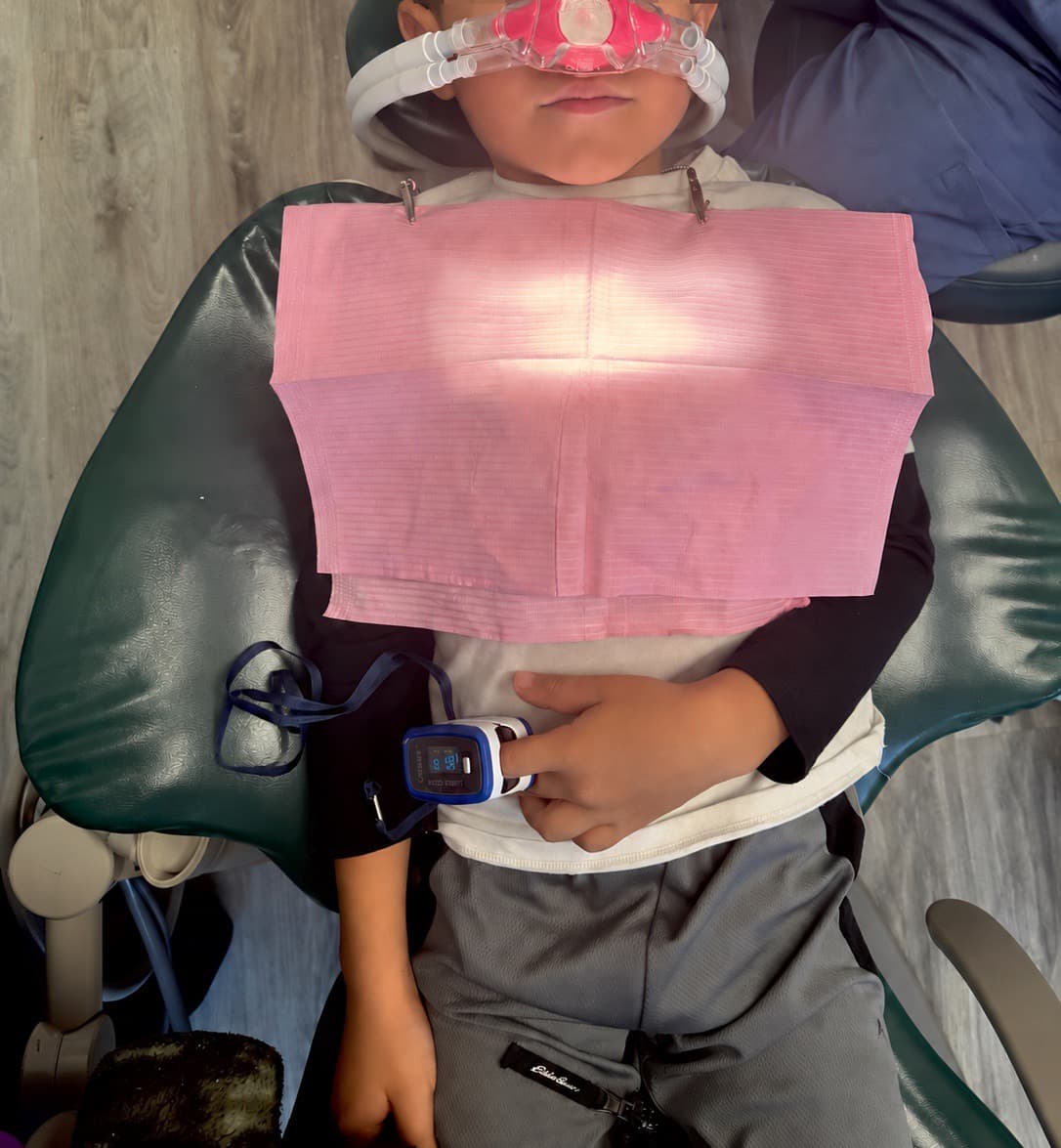 Enfant détendu avec le petit masque nasal rose du gaz hilarant