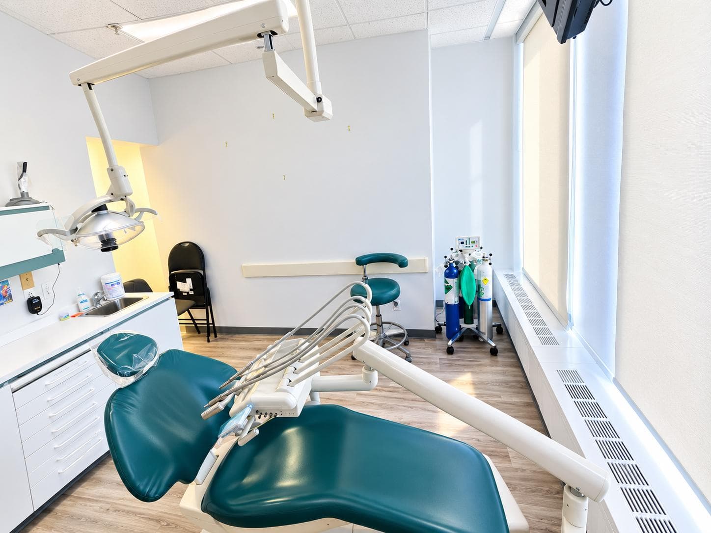 Salle de soins avec fauteuil dentaire, tabouret et fenêtre